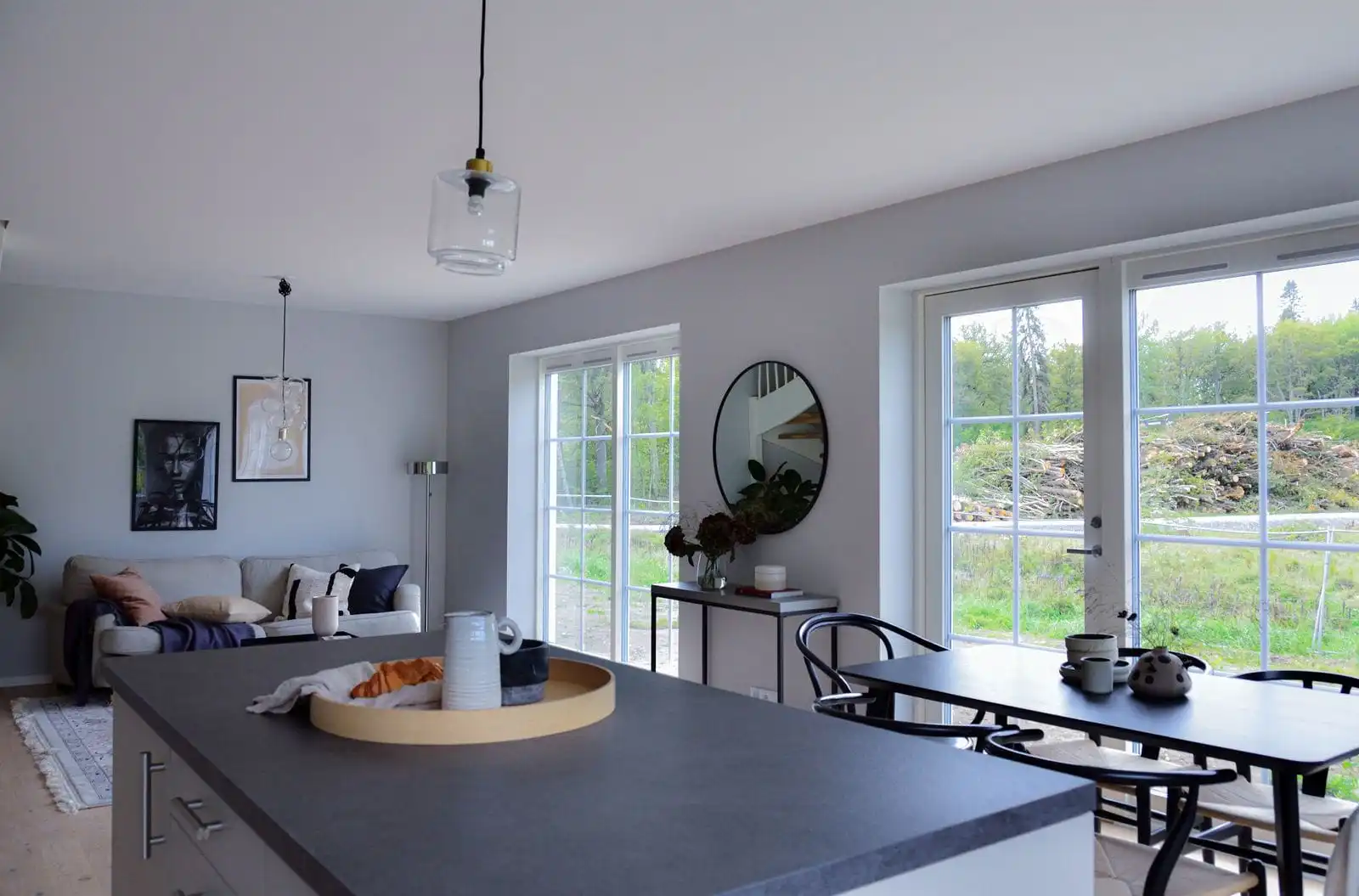 Open-plan living and kitchen with a dining table by large garden windows